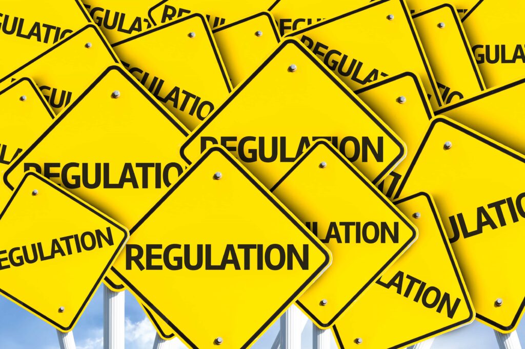 A collage of numerous yellow diamond-shaped traffic signs with the word "REGULATION" written in black, indicating various UK regulatory rules and guidelines, including ESG regulations. The signs overlap each other, creating a sense of abundance and complexity.