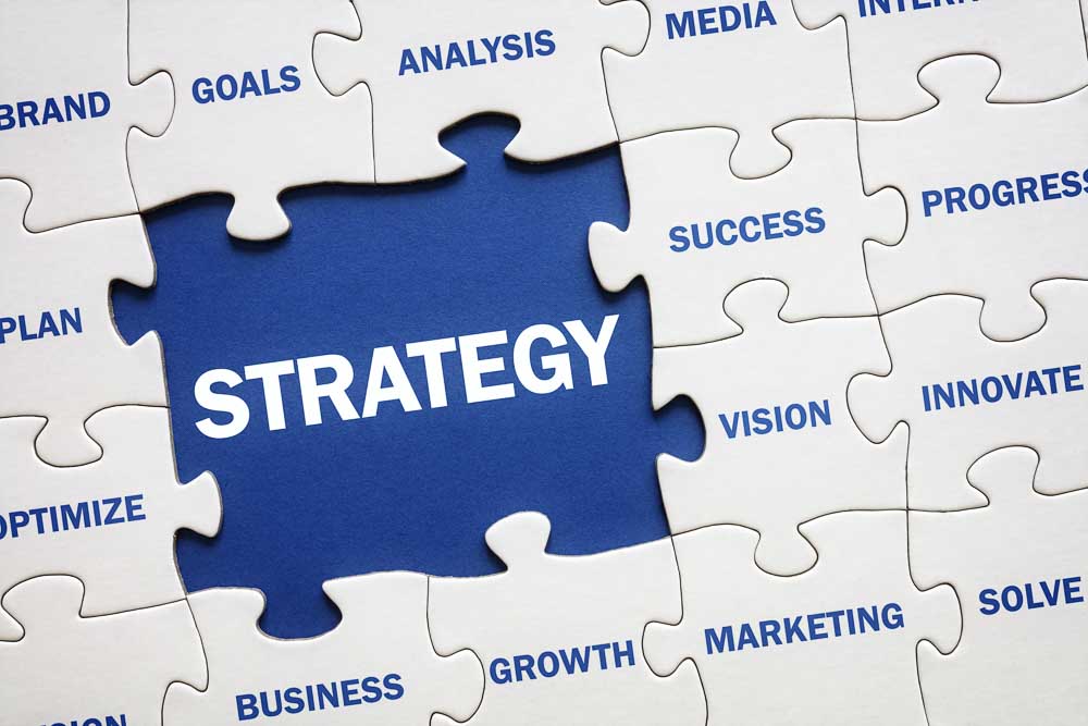 A blue puzzle piece with the word "STRATEGY" is surrounded by white pieces labeled "GOALS," "VISION," "ANALYSIS," "SUCCESS," and "INNOVATE." The image represents strategic planning and interconnected business concepts, emphasizing sustainability comparison in initiatives like those assessed by EcoVadis.