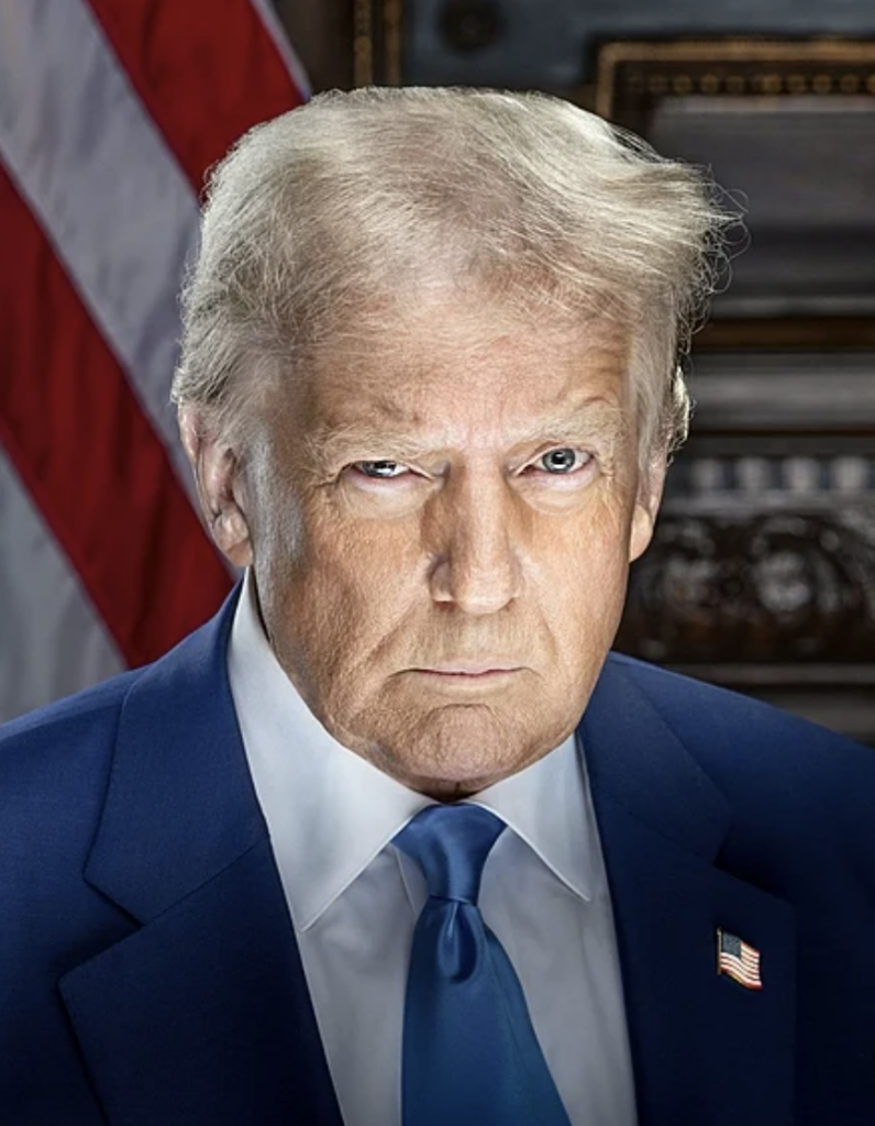 A man with light hair and a stern expression dons a blue suit, white shirt, and blue tie featuring an American flag pin. The backdrop reveals the stars and stripes, echoing themes of patriotism akin to Donald Trump's era.